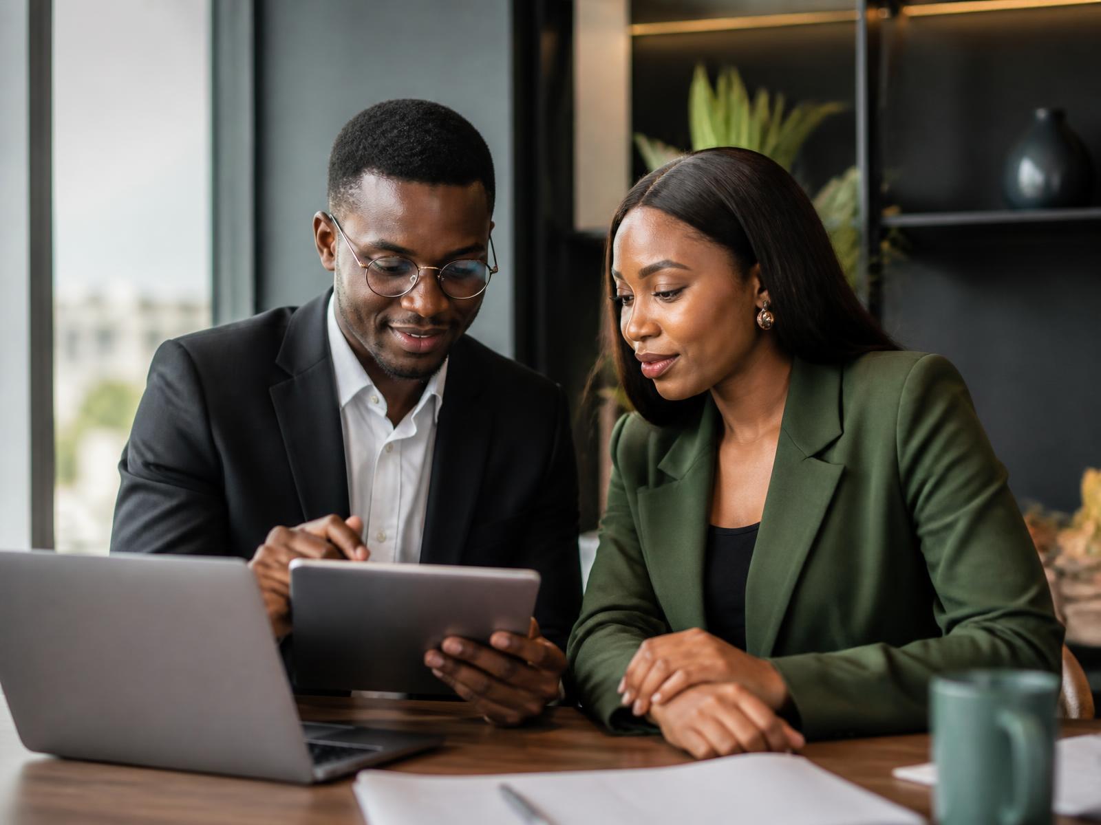 Two Nigerian business owners reviewing their company finances together in an office